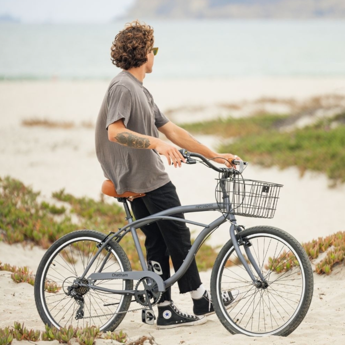 Man on beach holding bicycle with metal bike basket