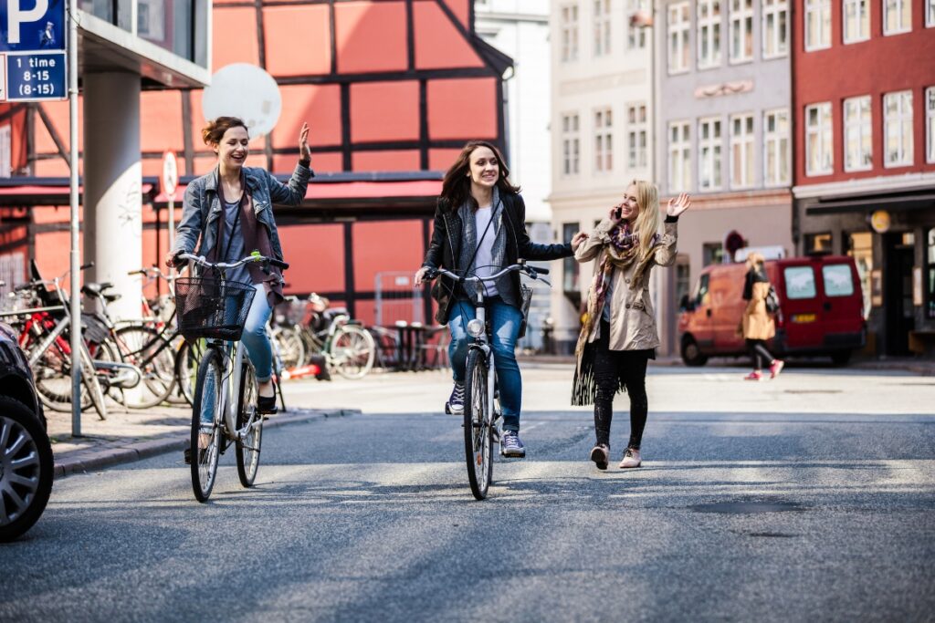 Two female cyclists riding bicycles down a street in copenhagen