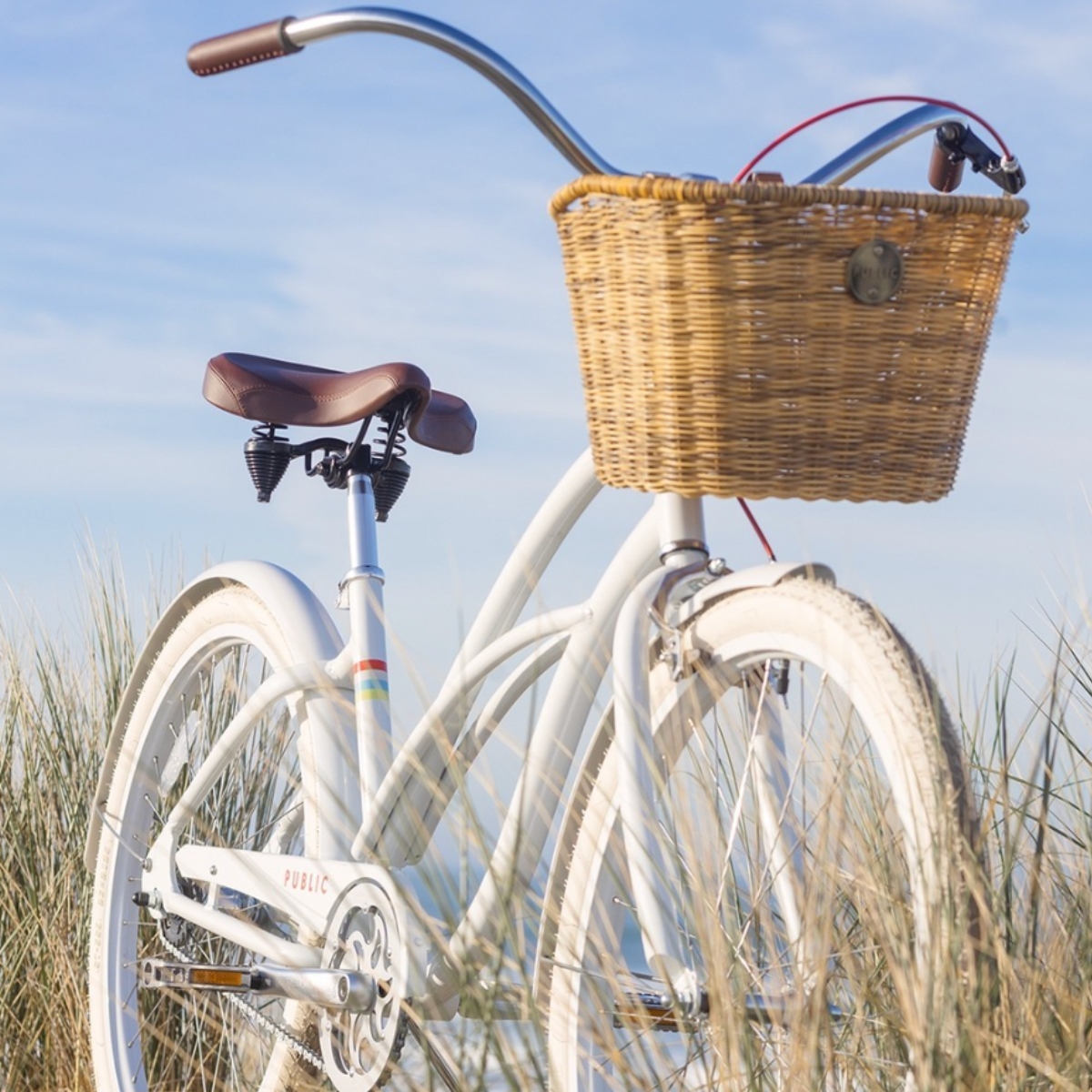 White bicycle with a wicker PUBLIC Bikes bike basket attached