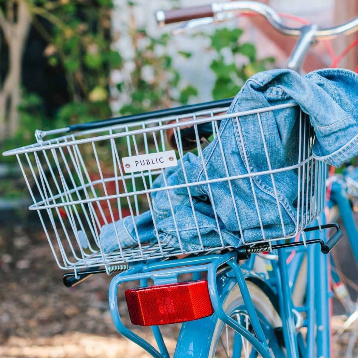A Public Bikes metal bicycle basket with a denim jacket in it