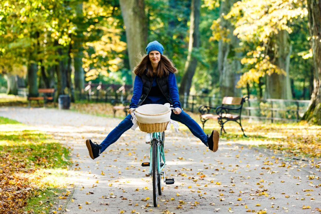 A woman on a bicycle riding joyfully through a park