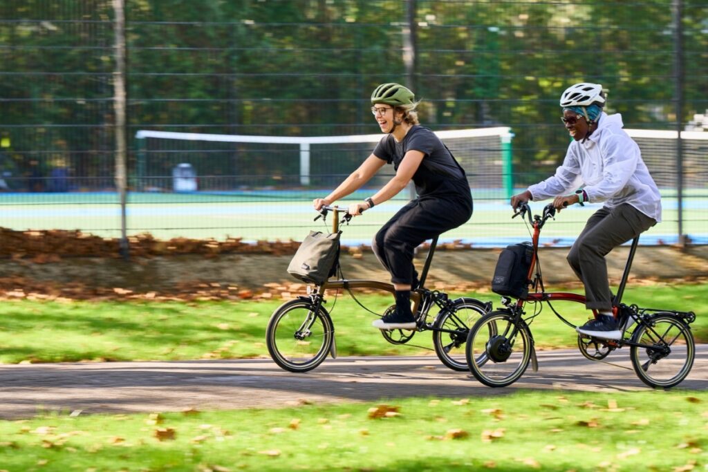 Man and woman riding Brompton Folding Bicycle in a park