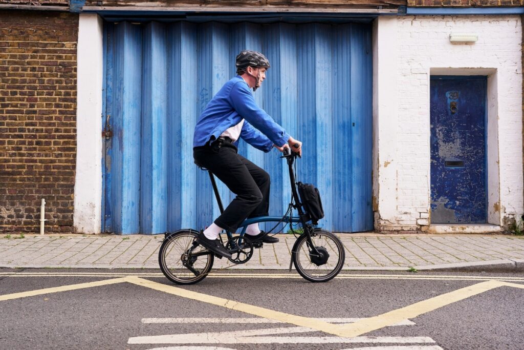 man in blue sweater riding Brompton Folding Bicycle