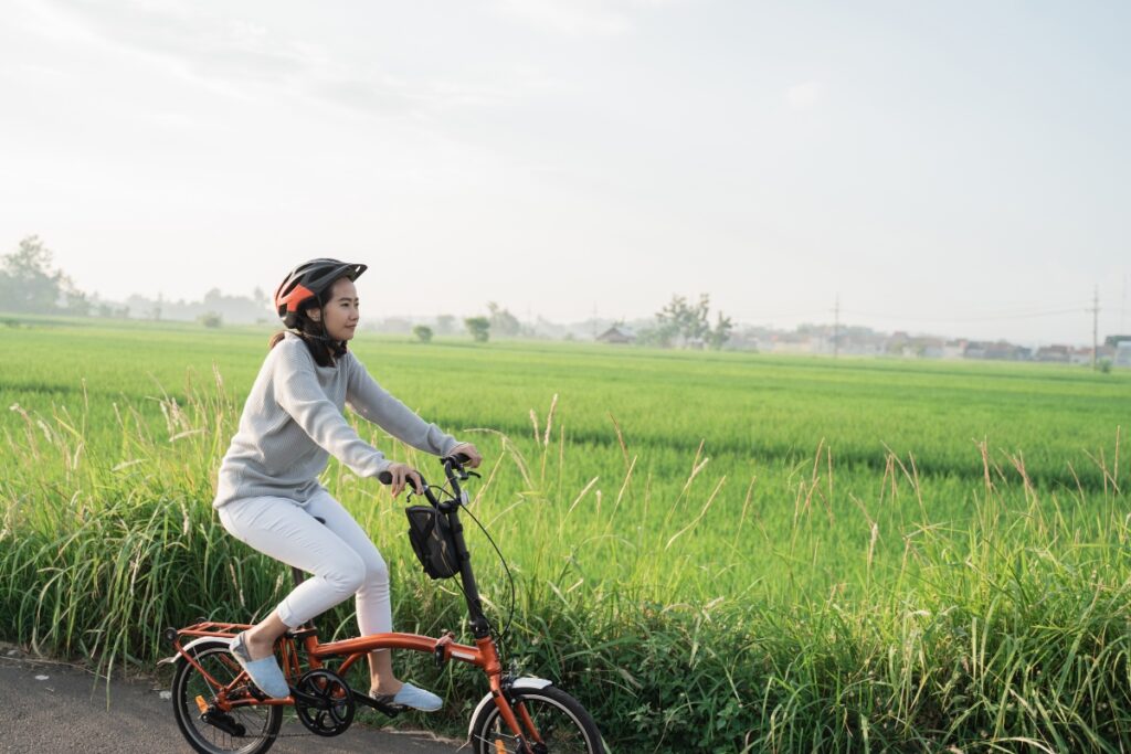 A woman riding a folding bike in a field