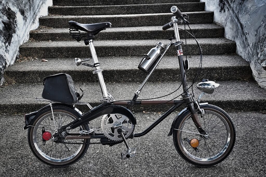 A silver folding bike standing in front of stairs